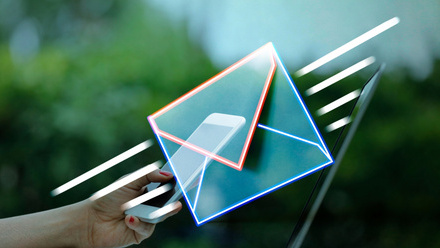 A glowing neon envelope with a smartphone inside, held by a hand against a blurred outdoor background, symbolizing digital communication.