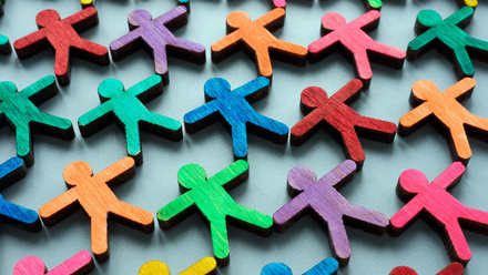 An arrangement of small, wooden, human-shaped figures painted in various bright colours, symbolising equality, equity, diversity and inclusion