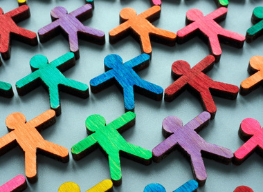 An arrangement of small, wooden, human-shaped figures painted in various bright colours, symbolising equality, equity, diversity and inclusion